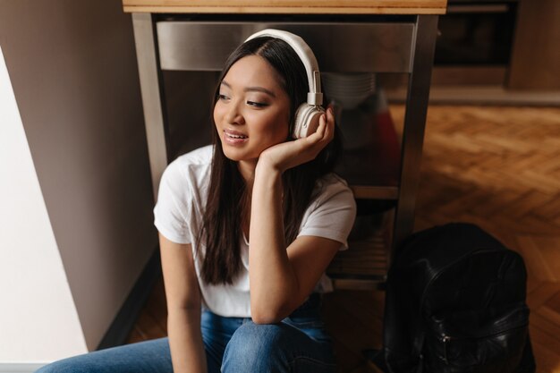 Mulher bonita com fones de ouvido, descansando e sentada no chão com fones de ouvido