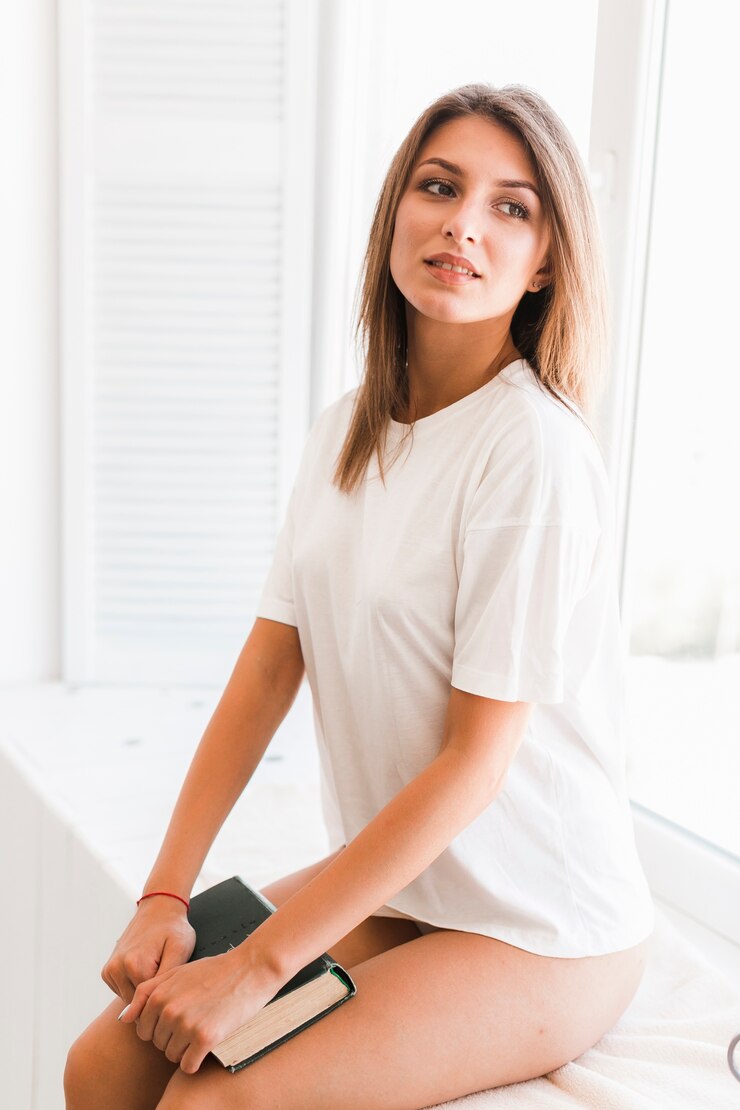 Foto grátis mulher bonita com livro sentado perto da janela