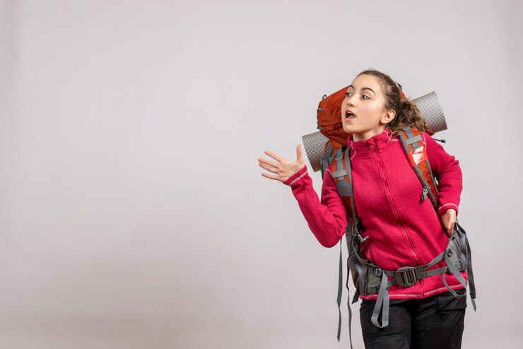 Foto grátis mulher bonita com mochila grande em pé acenando com a mão cinza