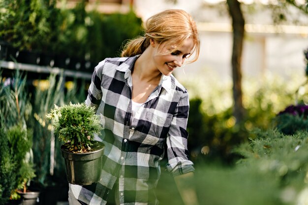 Mulher bonita com roupas fofas pegando as plantas na estufa