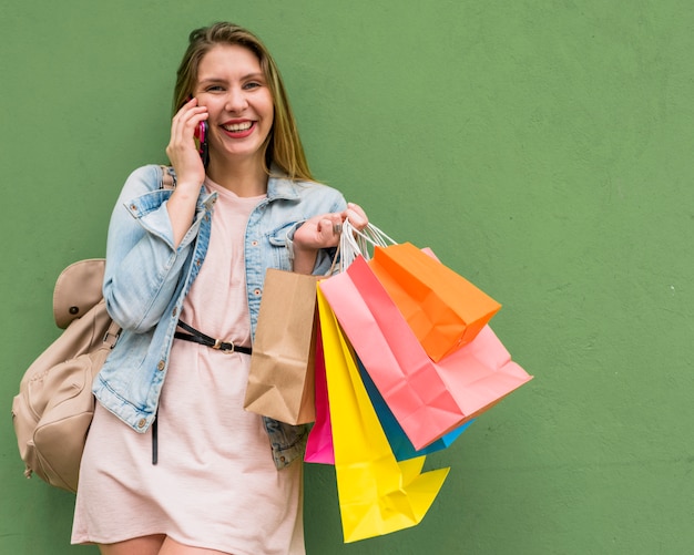 Foto grátis mulher bonita com sacos de compras brilhantes, falando por telefone