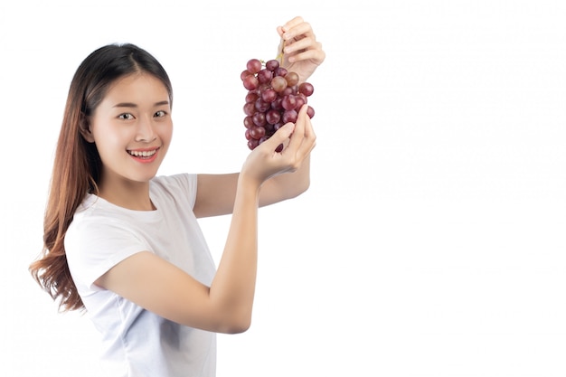Mulher bonita com um sorriso feliz que guarda uma uva da mão, isolada no fundo branco.