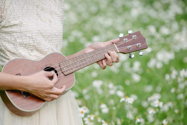 Mulher bonita com um vestido branco bonito e segurando um ukulele