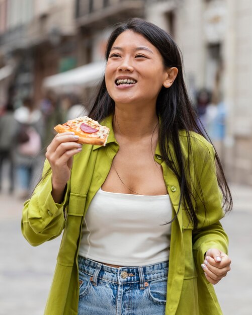 Mulher bonita comendo comida de rua ao ar livre