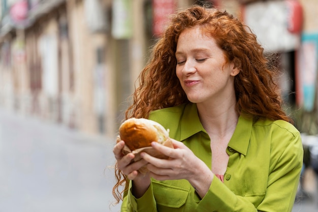 Mulher bonita comendo comida de rua ao ar livre