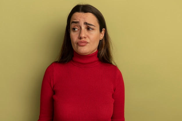 Foto grátis mulher bonita descontente olhando para o lado isolado na parede verde oliva