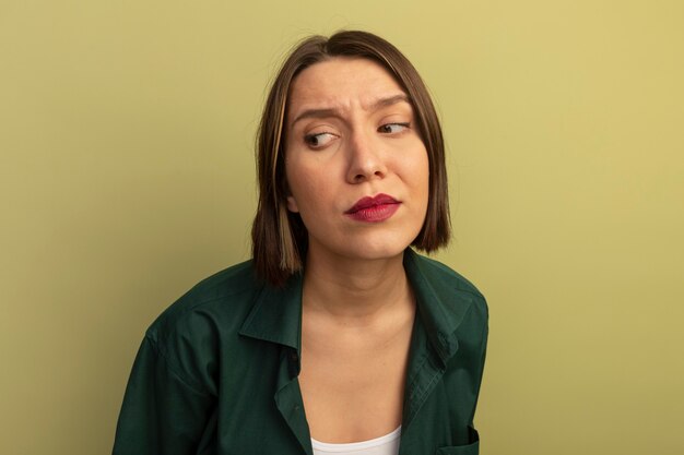 Foto grátis mulher bonita descontente olhando para o lado isolado na parede verde oliva