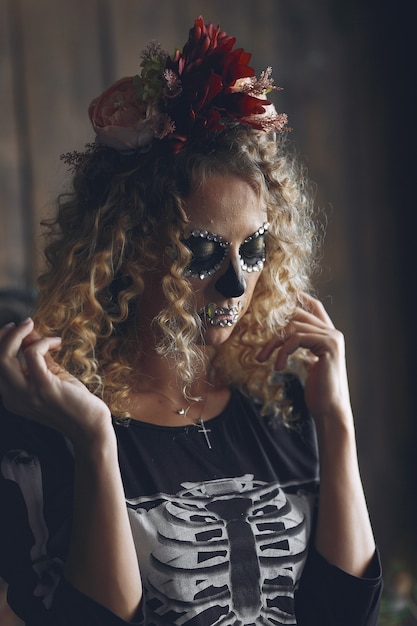 Mulher bonita do crânio de maquiagem de Halloween com penteado loiro. Menina modelo Santa Muerte em traje preto.