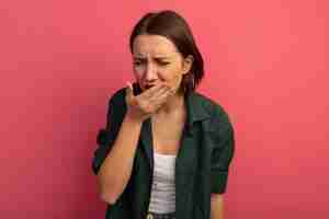 Foto grátis mulher bonita dolorida colocando a mão na boca isolada na parede rosa