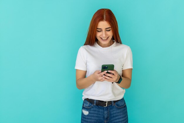 Mulher bonita e alegre usa seu smartphone para ler notícias e usa uma blusa de malha cinza isolada em azul-turquesa