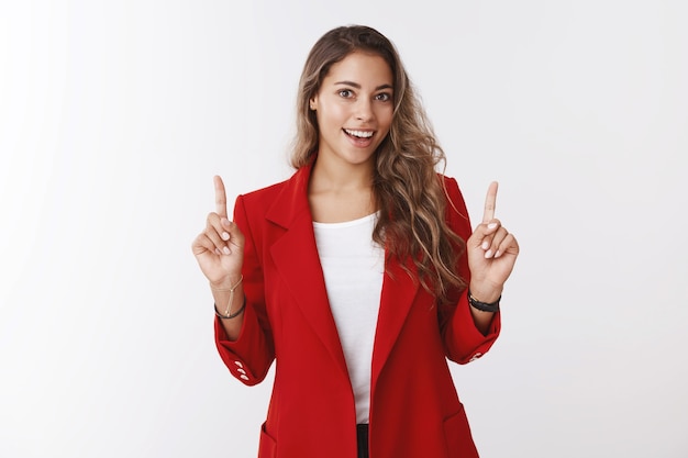 Mulher bonita e ambiciosa preparando uma apresentação de escritório de trabalho importante levantando o dedo indicador, mostrando o espaço da cópia superior sorrindo amplamente, sentindo-se sortuda, garantiu uma entrevista de sucesso