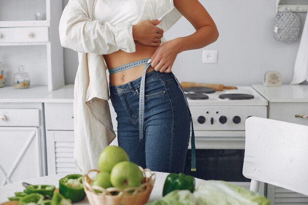 Mulher bonita e desportiva em uma cozinha com legumes