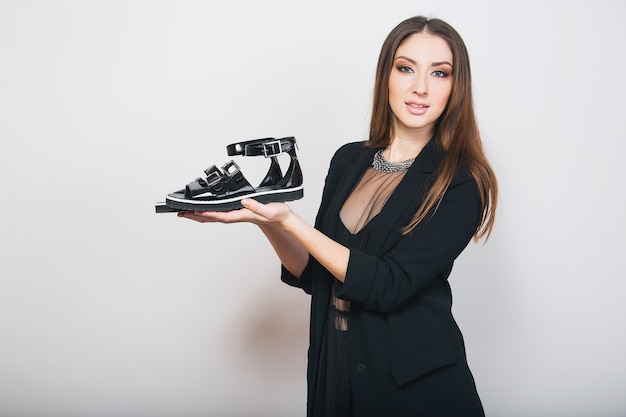 Foto grátis mulher bonita e elegante isolada em um terno preto segurando sapatos