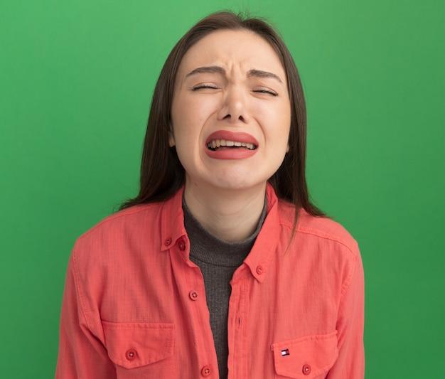 Foto grátis mulher bonita e jovem triste chorando com os olhos fechados, isolada na parede verde