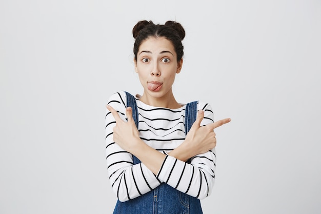 Foto grátis mulher bonita e perplexa mostra a língua, apontando para o lado nas promoções