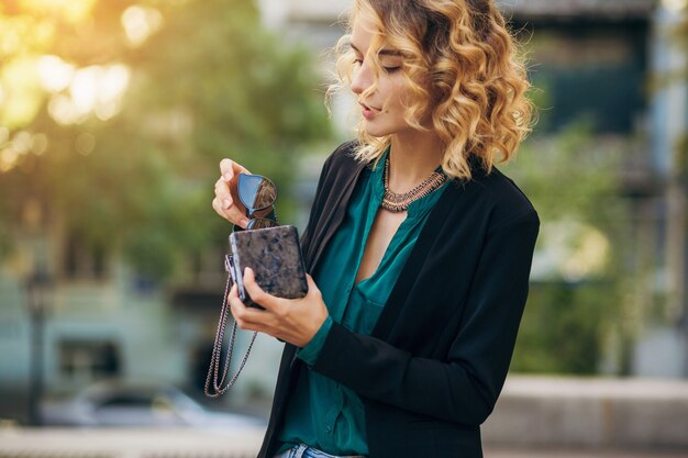 Mulher bonita elegante em jeans e jaqueta andando na rua com bolsinha, estilo elegante, tendências da moda de primavera