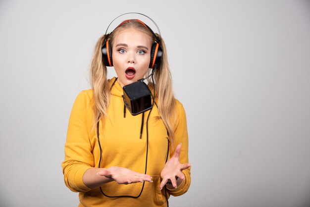 Mulher bonita em fones de ouvido, brincando com um relógio.