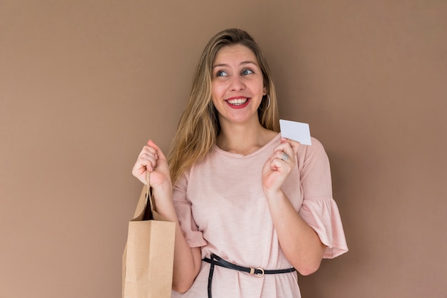 Mulher bonita em pé com a sacola de compras e cartão de crédito