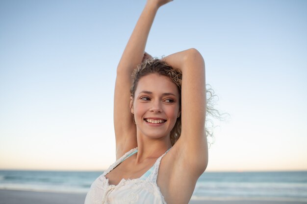 Mulher bonita em pé com os braços para cima na praia