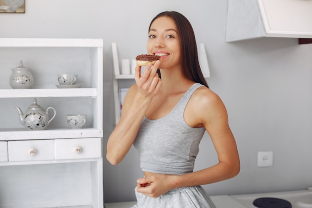 Mulher bonita em pé em uma cozinha com rosquinha