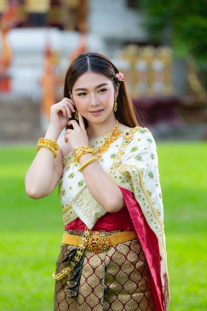 Mulher bonita em roupa tradicional tailandesa sorrindo e em pé no templo