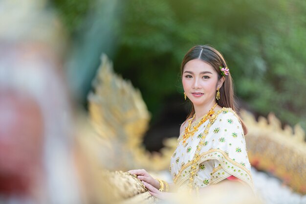 Mulher bonita em roupa tradicional tailandesa sorrindo e em pé no templo