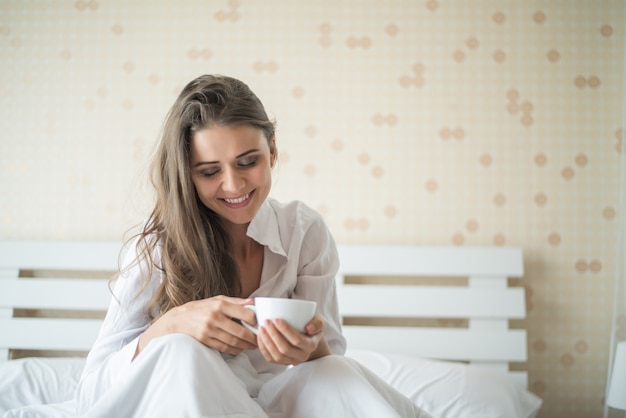 Mulher bonita em seu quarto tomando café da manhã