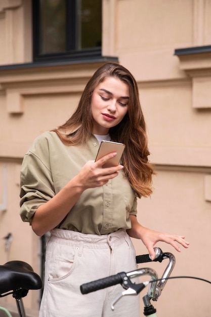 Mulher bonita em sua bicicleta olhando para o smartphone