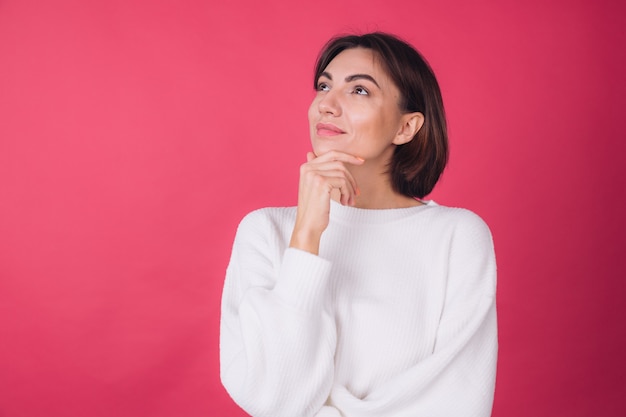 Foto grátis mulher bonita em suéter branco casual na parede vermelha