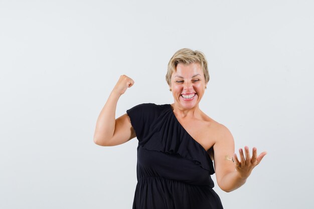 Mulher bonita em uma blusa preta posando como se estivesse segurando o telefone enquanto mostra o gesto do vencedor e está linda