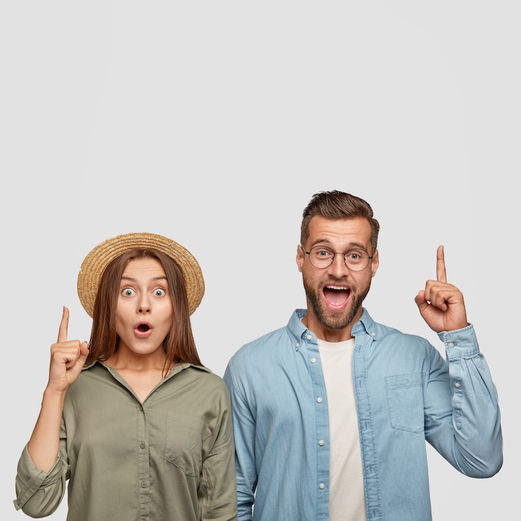 Foto grátis mulher bonita espantada e cara bonito e alegre surpreso apontam juntos para cima, mostram espaço livre para propaganda