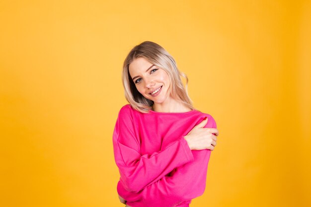 Mulher bonita europeia com blusa rosa na parede amarela