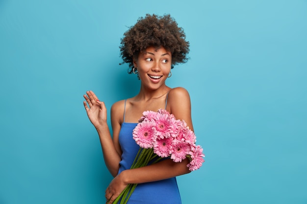 Mulher bonita feliz e elegante com um buquê de gérbera rosa, recebendo flores