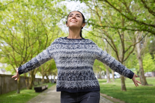 Foto grátis mulher bonita feliz espalhando as mãos e andando no parque