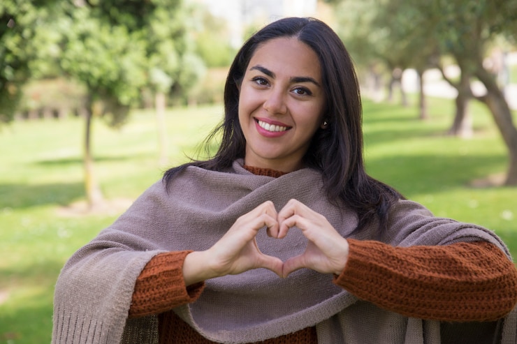 Foto grátis mulher bonita feliz fazendo um gesto de coração no parque da cidade