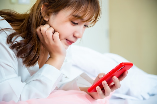 Mulher bonita feliz usando smartphone na cama