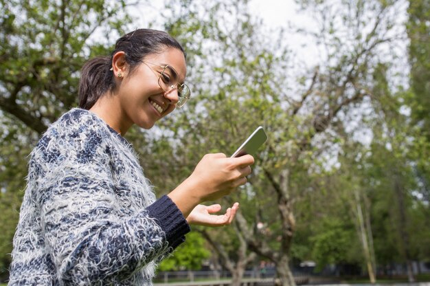 Mulher bonita feliz usando smartphone no parque