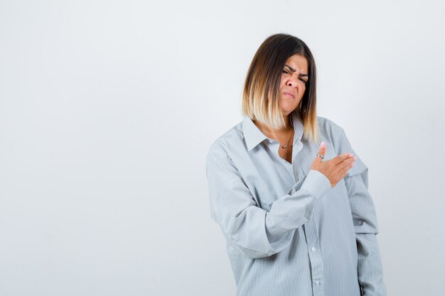 Mulher bonita fingindo mostrar algo na camisa e parecendo enojada. vista frontal.