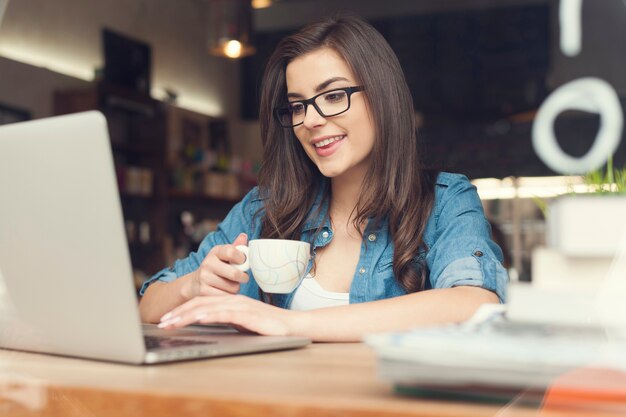 Mulher bonita hippie usando laptop no café