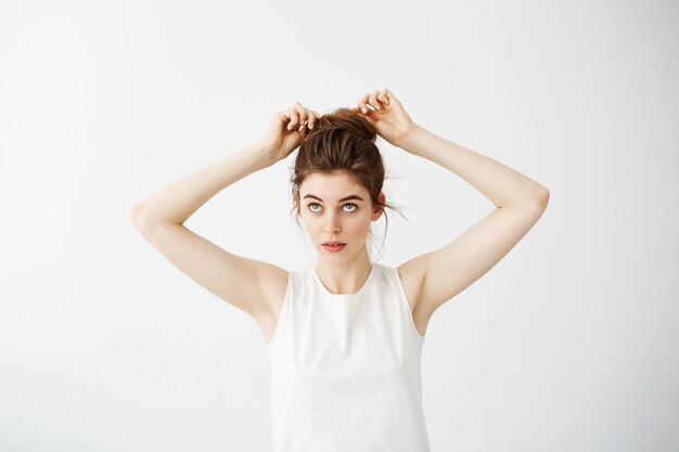 Mulher bonita jovem, corrigindo o bolo de cabelo