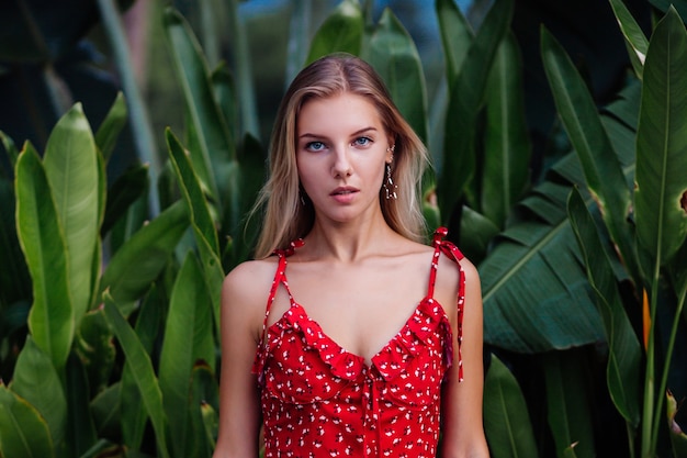 Mulher bonita jovem de beleza natural de retrato de moda ao ar livre com maquiagem leve, brincos de estrela, pulseira e anel. mulher com vestido de flor vermelha de verão