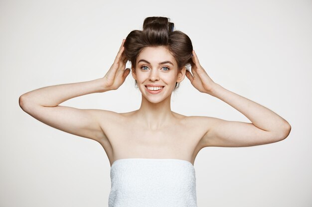 Mulher bonita jovem engraçada em rolos de cabelo e toalha posando. Cosmetologia de beleza e spa.