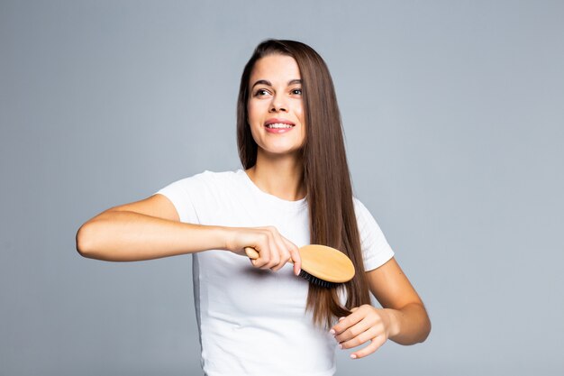 Mulher bonita jovem, penteando o cabelo isolado no branco