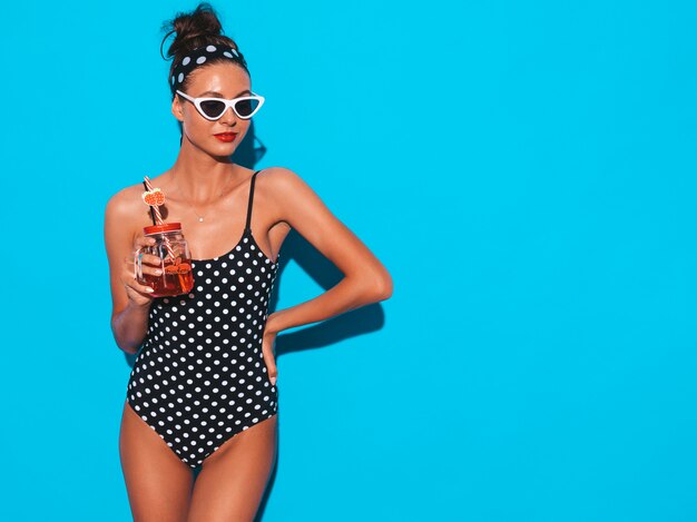 Mulher bonita jovem sorridente sexy hipster em óculos de sol. Garota de maiô de ervilhas de verão maiô.