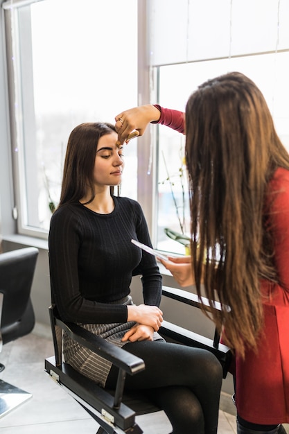 Mulher bonita modelo no salão de beleza está fazendo maquiagem de noite