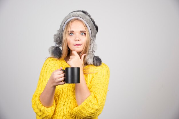 Mulher bonita no suéter amarelo, posando com uma xícara de chá.