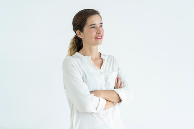 Mulher bonita nova de sorriso que está com braços cruzados.