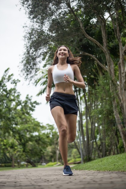 Mulher bonita nova do esporte que corre no parque. Conceito de saúde e esporte.