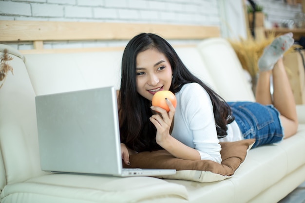 Mulher bonita nova que usa um laptop em casa.