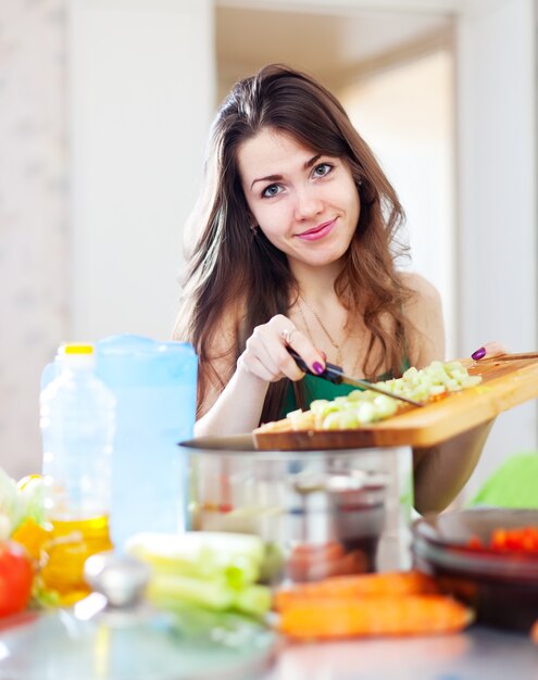 mulher bonita que cozinha salada vegetariana